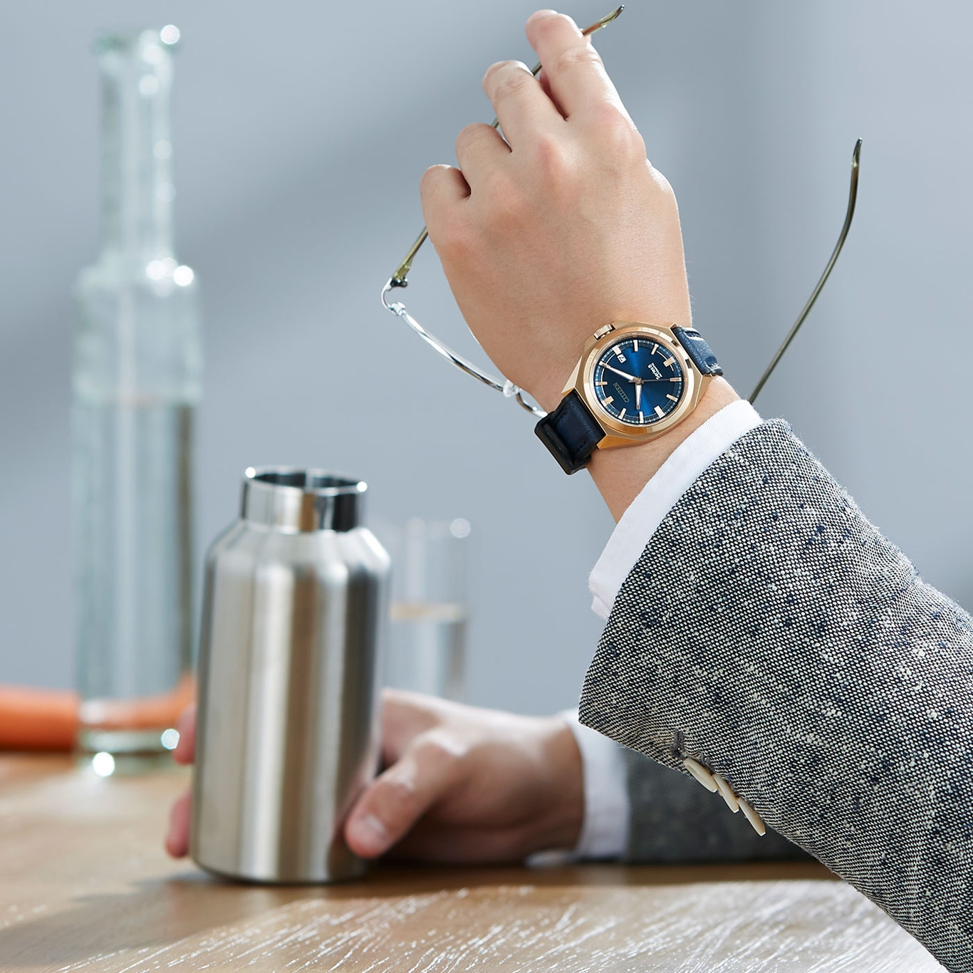 Man met horloge, bril, waterfles op tafel. Zakenman in pak.