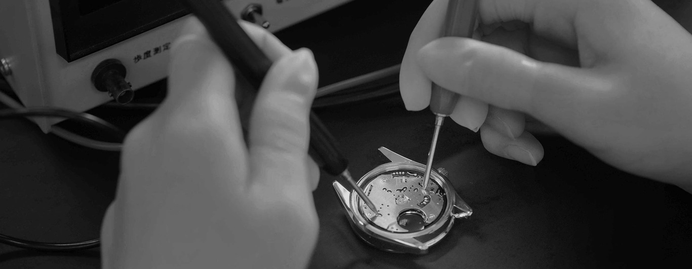 Horlogereparatie met gereedschap en handen, close-up, zwart-wit, precisiewerk.