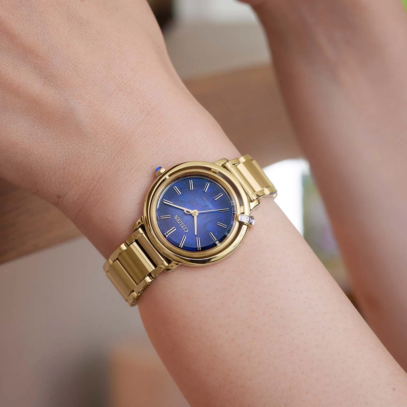 Gouden horloge om de pols met blauwe wijzerplaat, merk Citizen, close-up