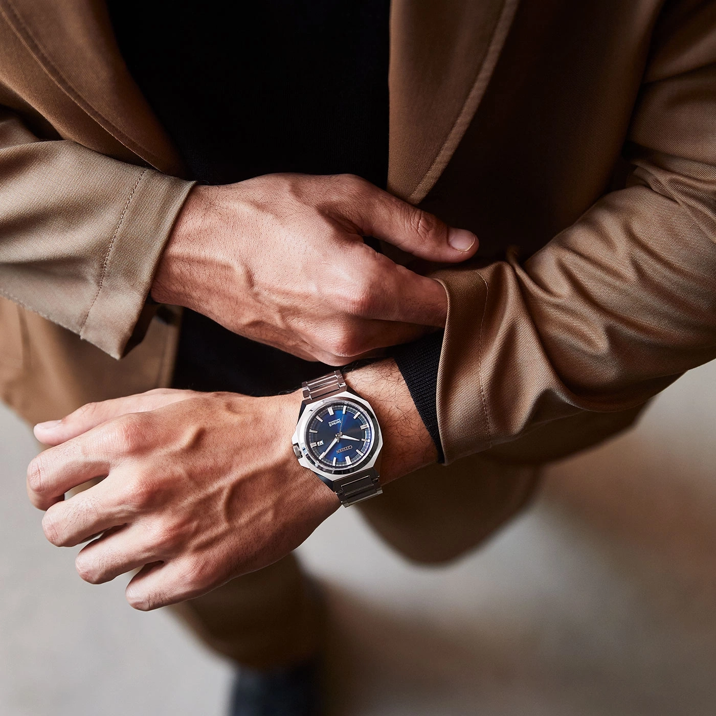 Man met horloge, colbert en zwart overhemd, close-up.