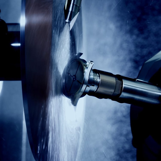 Metaalbewerking met roterend gereedschap en waterspray, close-up opname.