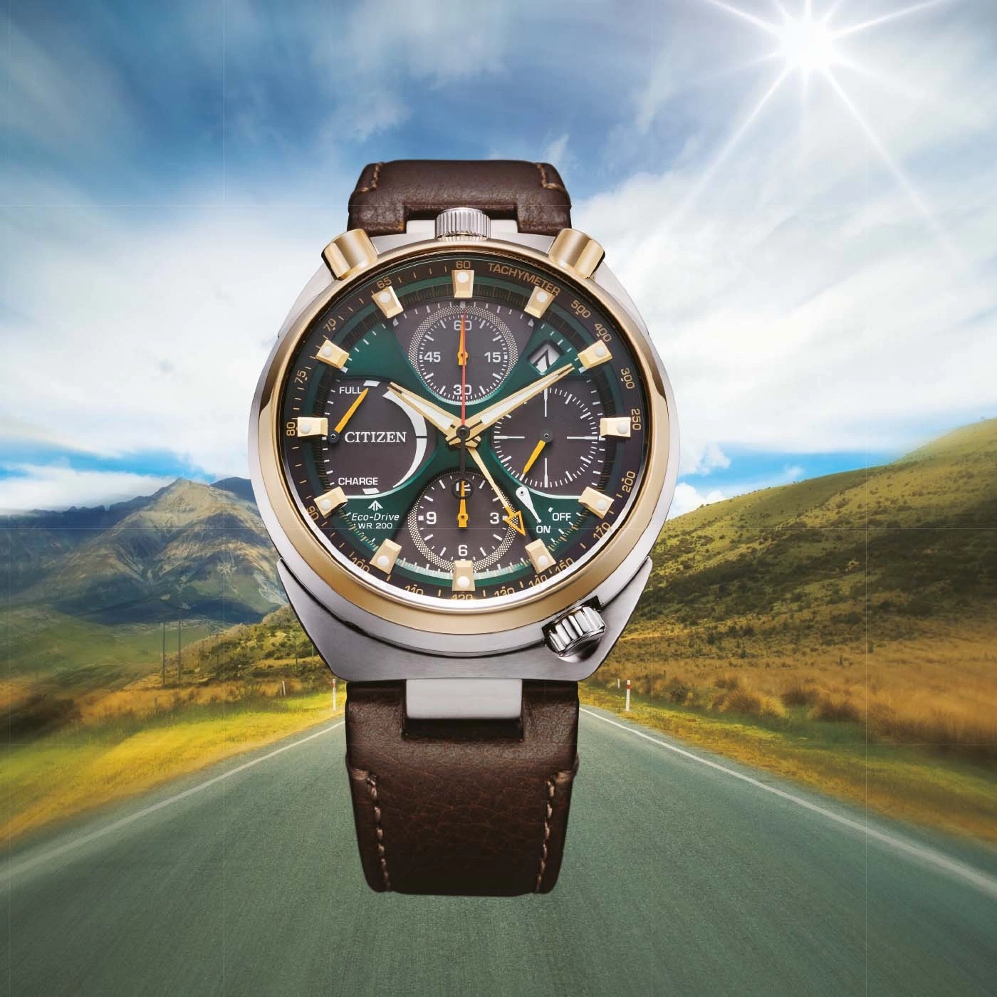 Een Citizen Eco-Drive horloge op een schilderachtige weg met bergen en zon.