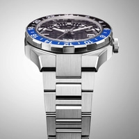 Close-up van een zilveren horloge met een blauw-zwarte bezel en een metalen band.