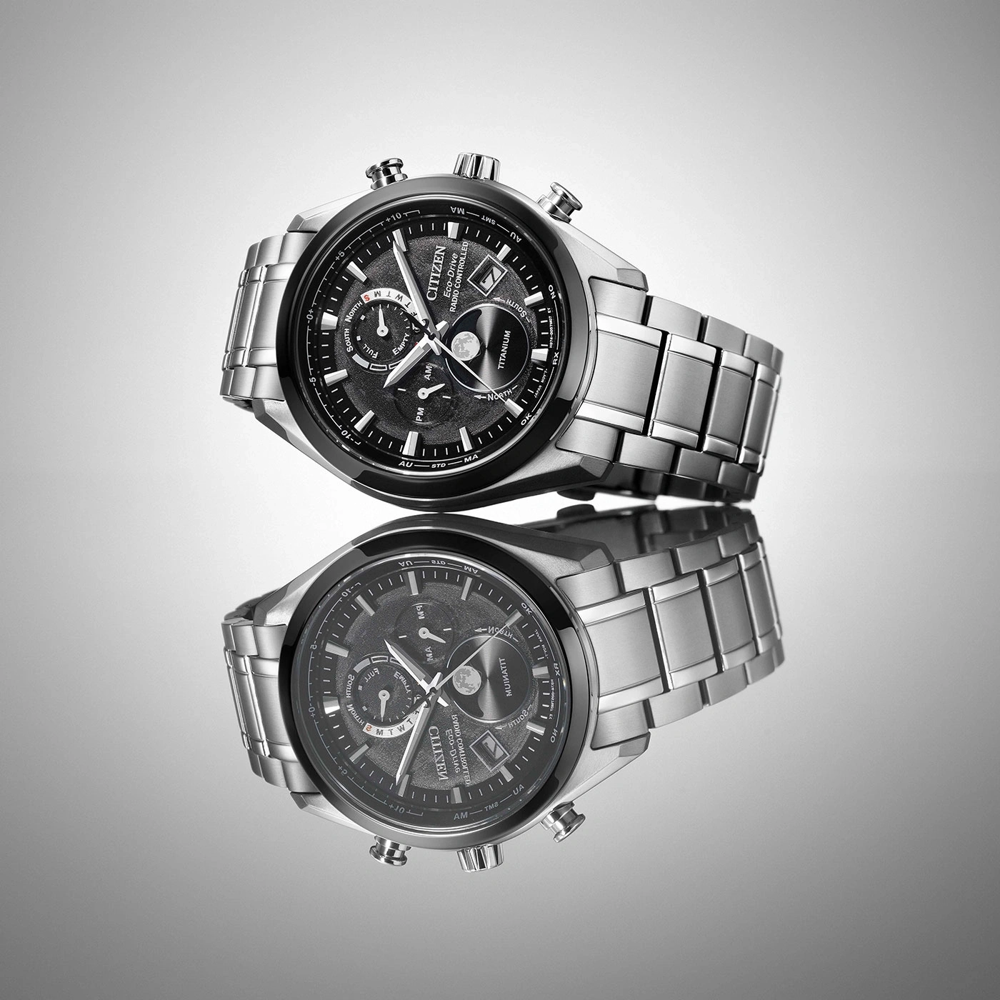 Citizen horloge met zwarte wijzerplaat en zilveren band, weerspiegeld op een oppervlak.