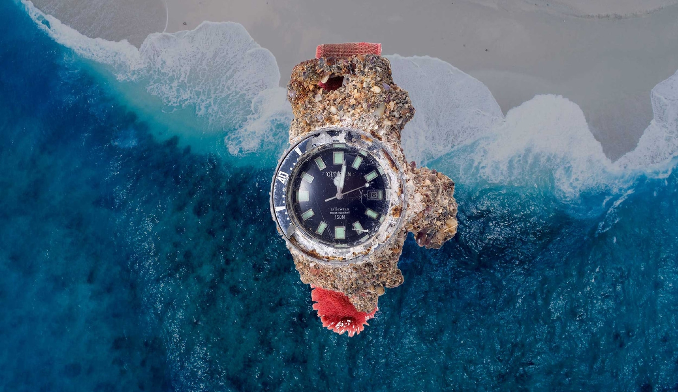 Een horloge bedekt met zeepokken in de oceaan, met een strand op de achtergrond.