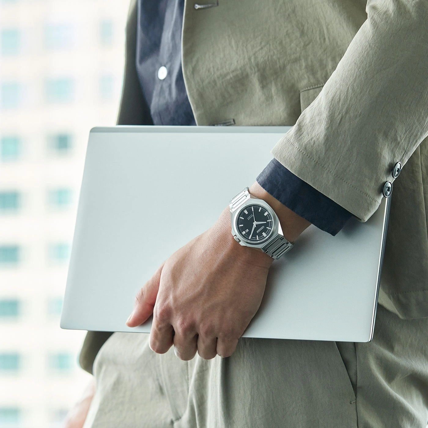 Man met laptop, draagt horloge en pak. Zakelijke professional.
