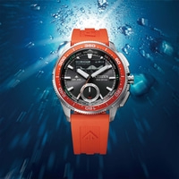 Een duikhorloge met oranje band in blauw water.