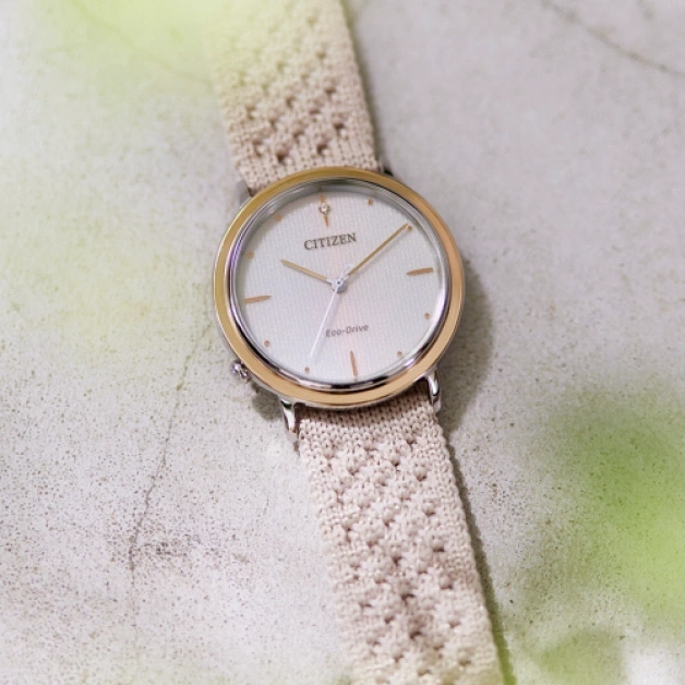 Citizen horloge met crèmekleurige band op een getextureerd oppervlak