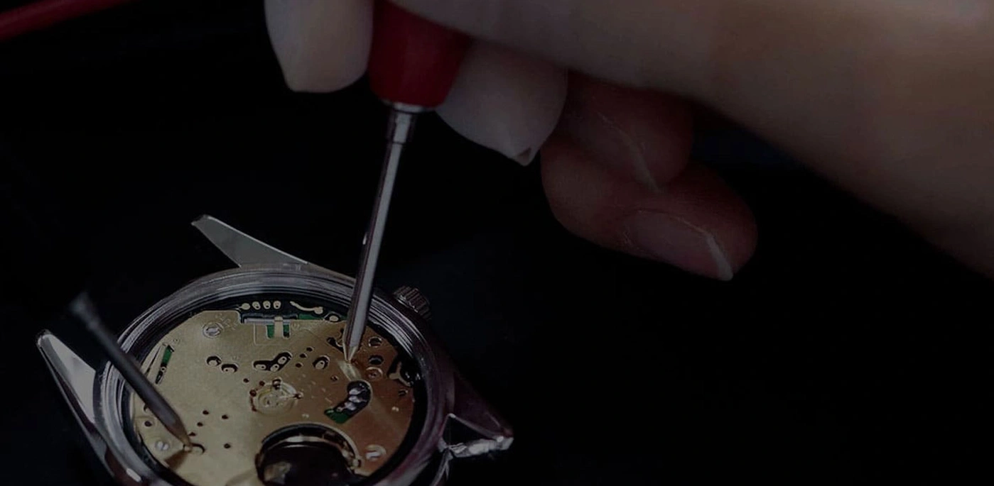 Horlogereparatie met gereedschap en handen, close-up, zwarte achtergrond