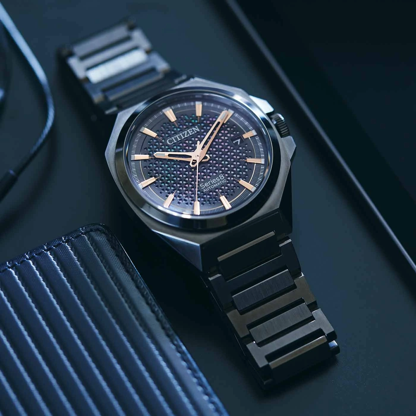 Citizen Series 8 automatische horloge op een donker oppervlak met een portemonnee.