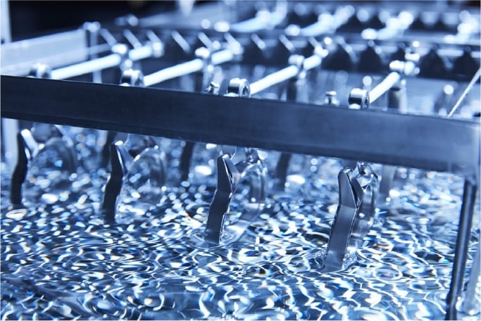 Metalen onderdelen die in een vloeistof worden gedompeld, industrieel proces, close-up.