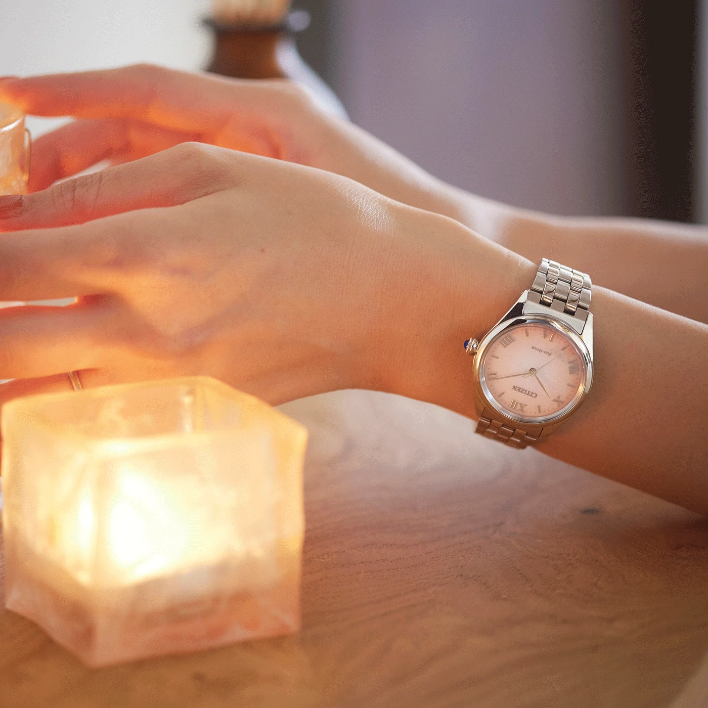 Pols met horloge, brandende kaars en houten tafel. Sfeervol.