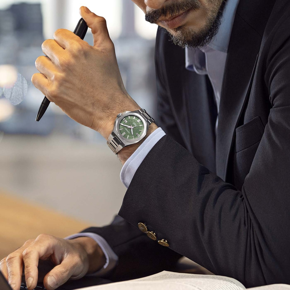 Man in pak met horloge en pen aan bureau