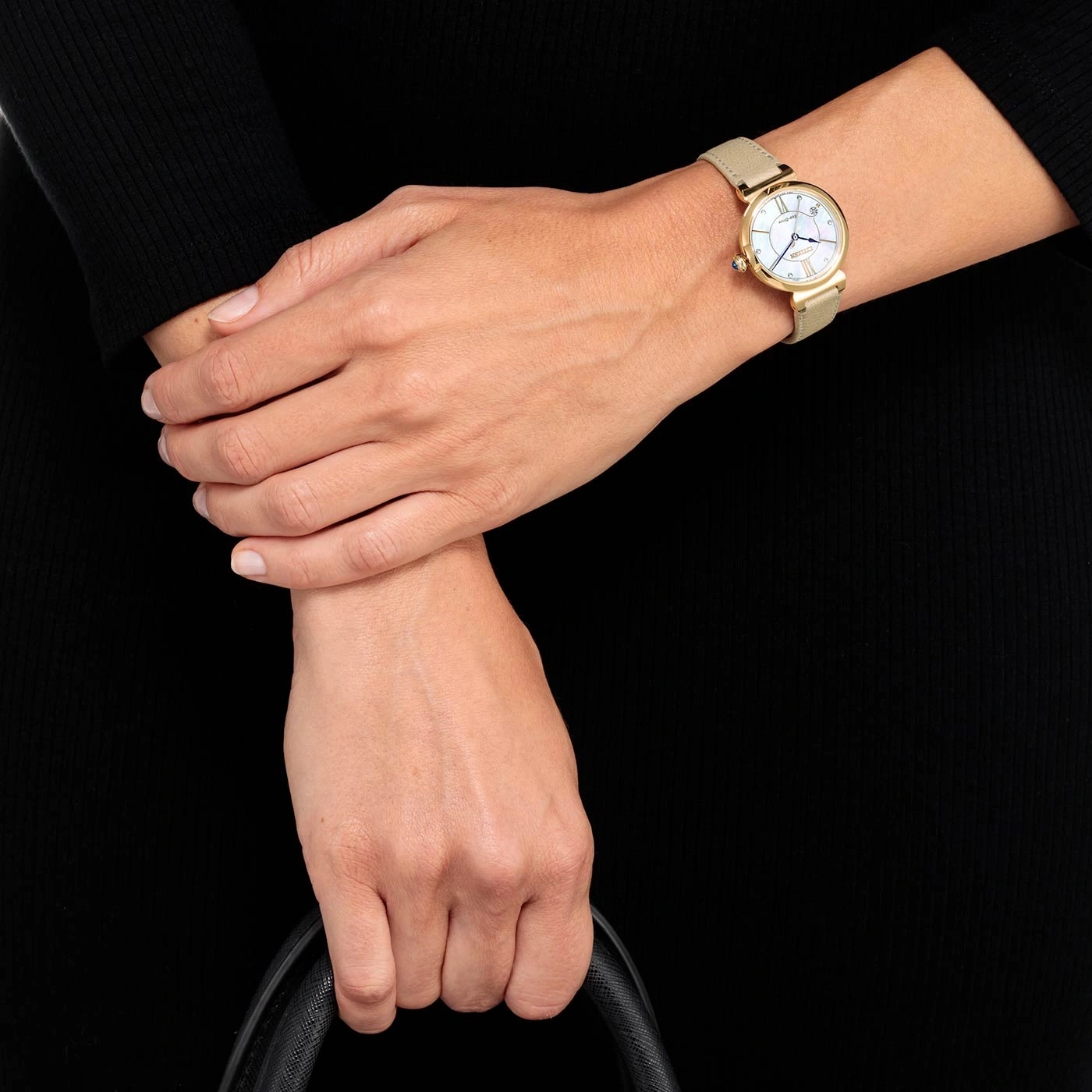 Vrouw met gouden horloge, zwarte tas, zwarte jurk