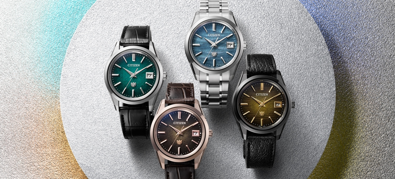 Vier Citizen horloges met verschillende gekleurde wijzerplaten en bandjes op een getextureerde achtergrond.