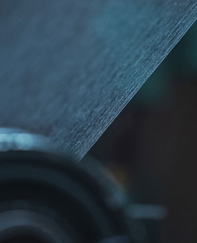 Close-up van getextureerd papier met een donkere, vage achtergrond en zachte belichting.