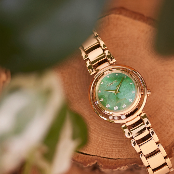 Gouden Citizen horloge met groene wijzerplaat en diamanten op houten oppervlak.