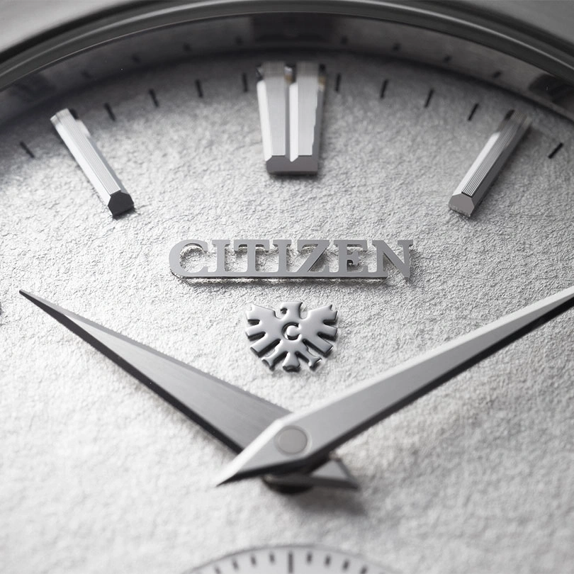Close-up van een Citizen horlogekast met zilveren wijzers en markeringen.