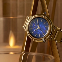 Gouden Citizen horloge met een blauwe wijzerplaat, elegant en stijlvol, met een kaars op de achtergrond.