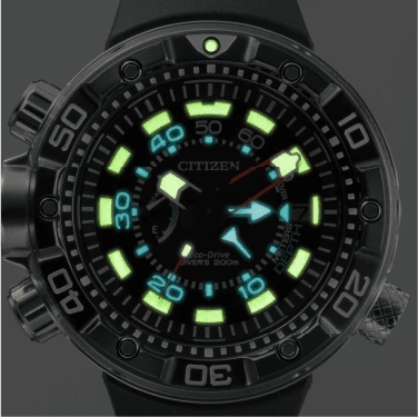 Close-up van een Citizen Eco-Drive duikhorloge met lichtgevende wijzers en markeringen, zwarte lunette.
