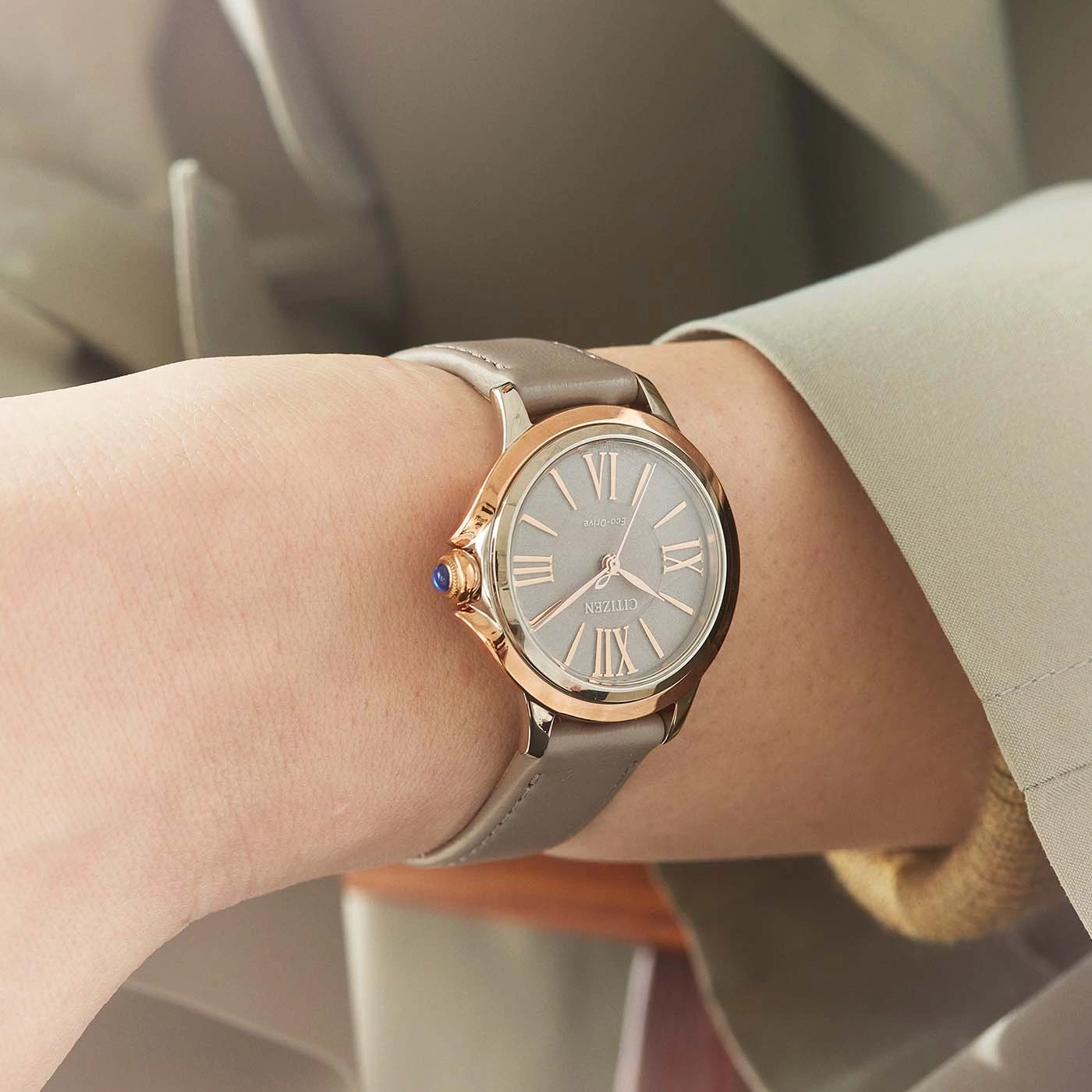 Close-up van een Citizen horloge om een pols, met een grijze band en roségouden accenten.