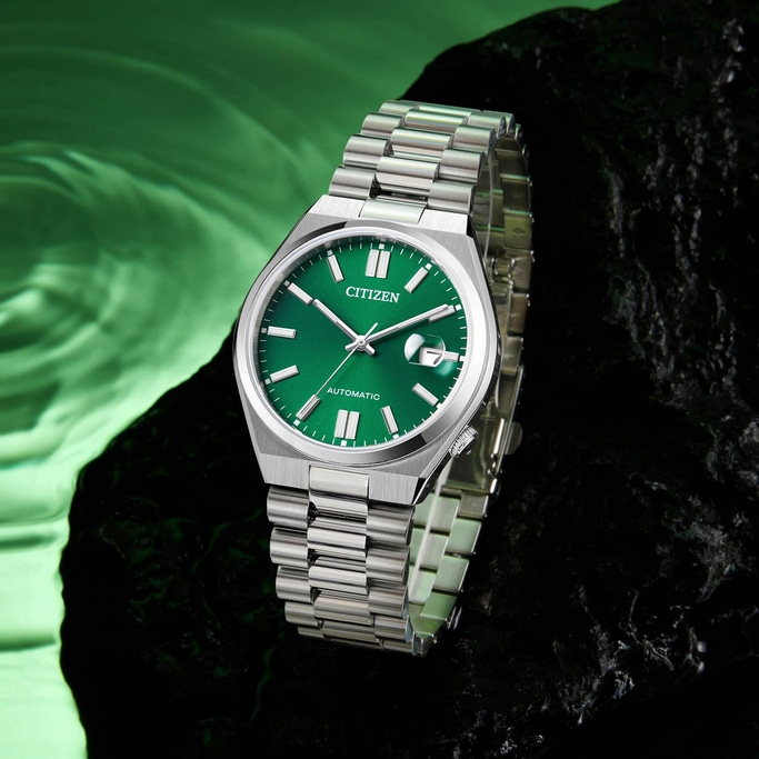 Citizen horloge met groene wijzerplaat en zilveren band op donkere ondergrond.