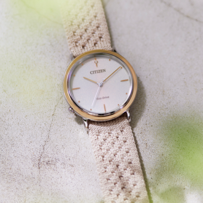 Citizen horloge met crèmekleurige band op een getextureerd oppervlak