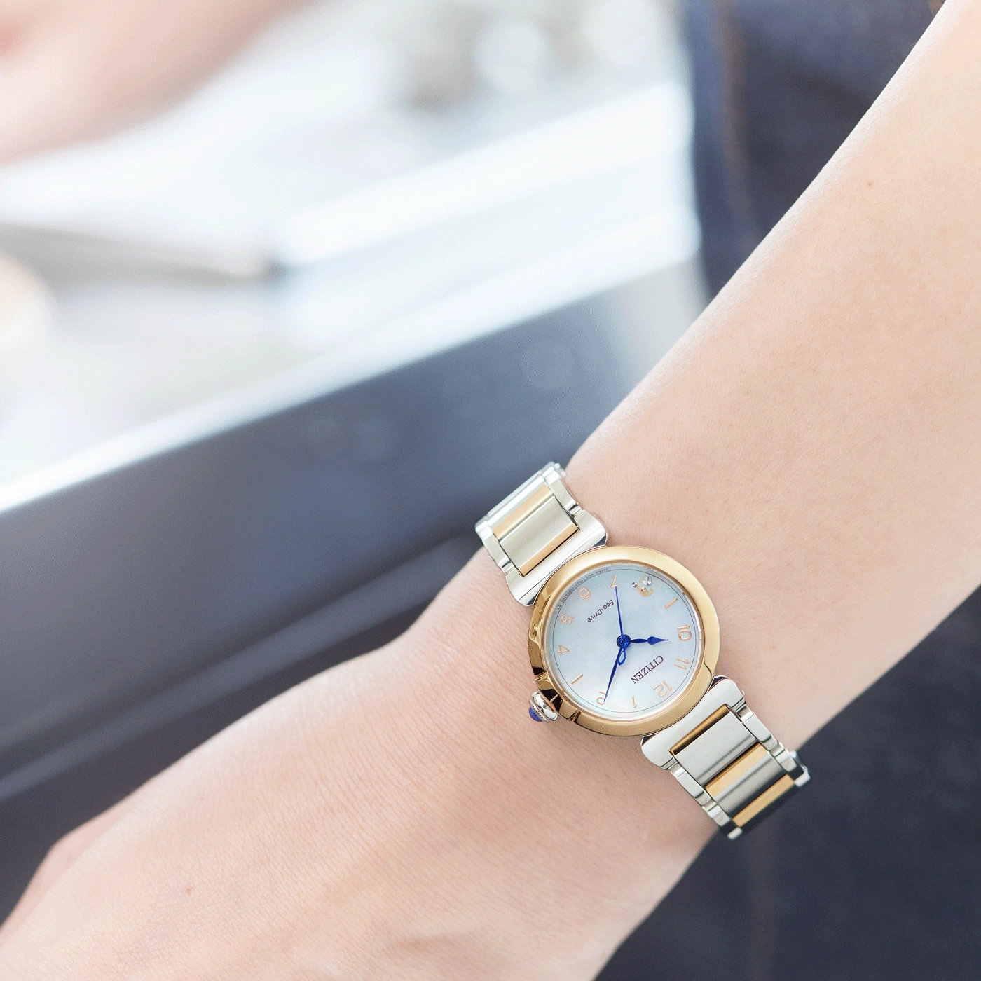 De pols van een vrouw met een Citizen Eco-Drive horloge, goud en zilver.