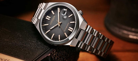 Citizen horloge met zwarte wijzerplaat en zilveren armband op een boek