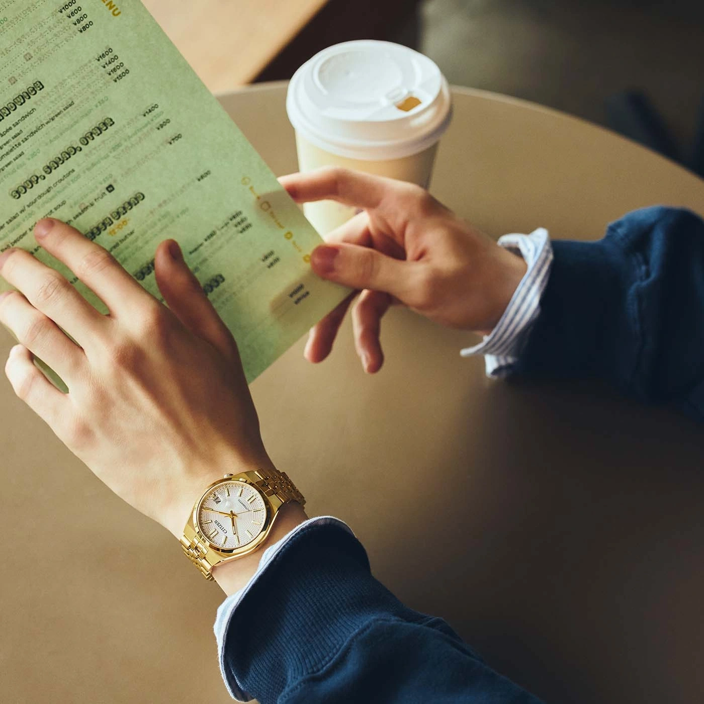 Een persoon bekijkt een menu en houdt een koffiekop vast.