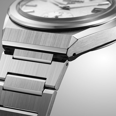 Close-up van een zilveren horloge met een geborstelde metalen afwerking en een witte wijzerplaat.