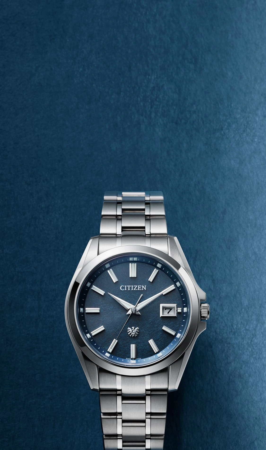Citizen horloge met blauwe wijzerplaat en zilveren band op blauwe achtergrond.