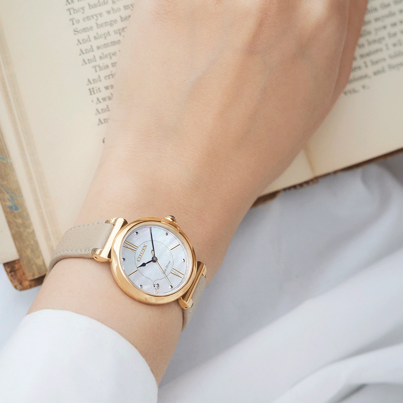 Pols horloge om de pols, gouden horloge met lichtgekleurde band, Citizen horloge.