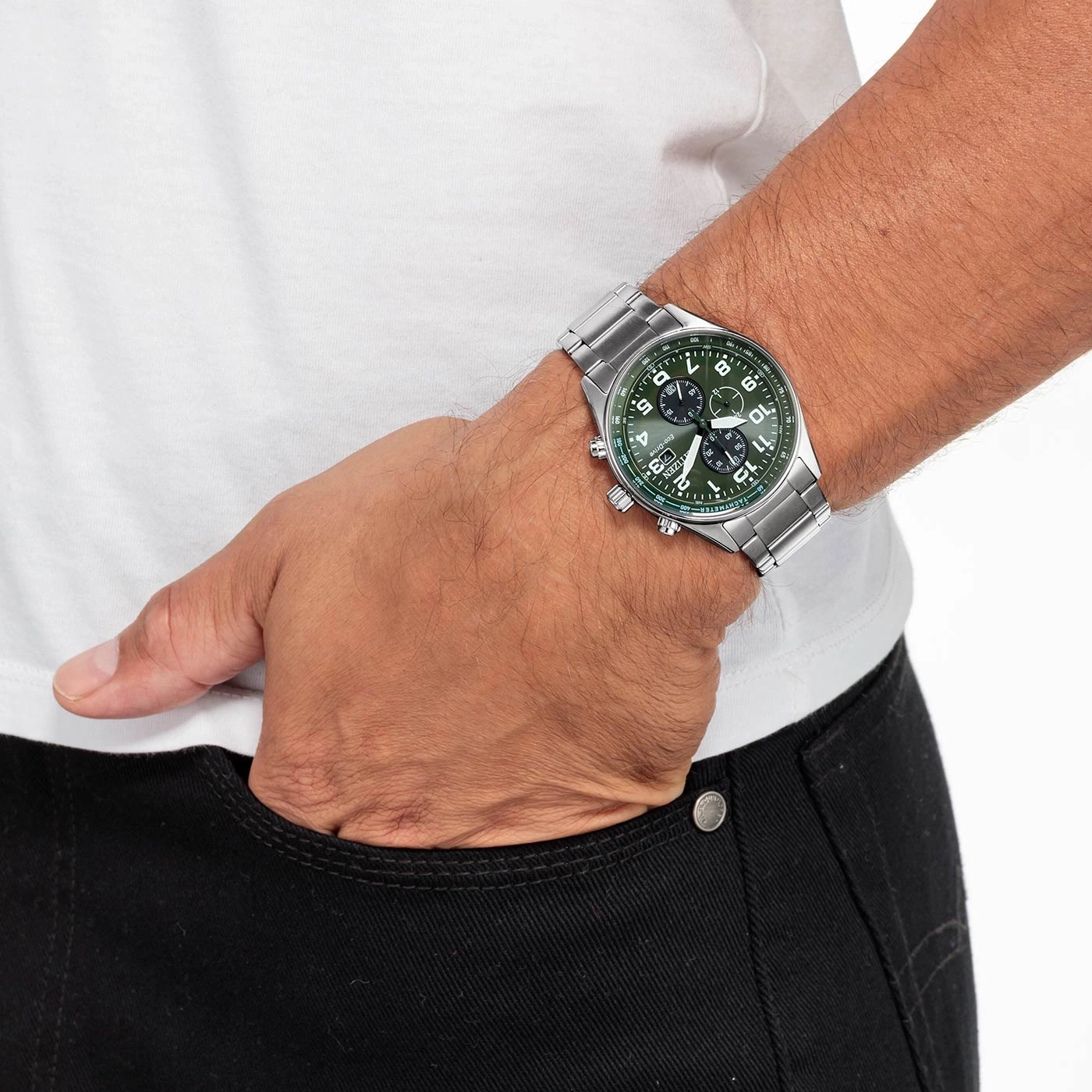 Man met zilveren horloge met groene wijzerplaat, hand in de zak.