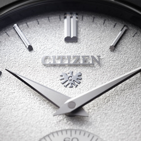 Nahaufnahme eines Citizen-Zifferblatts mit silbernen Zeigern und Logo auf strukturiertem Hintergrund.