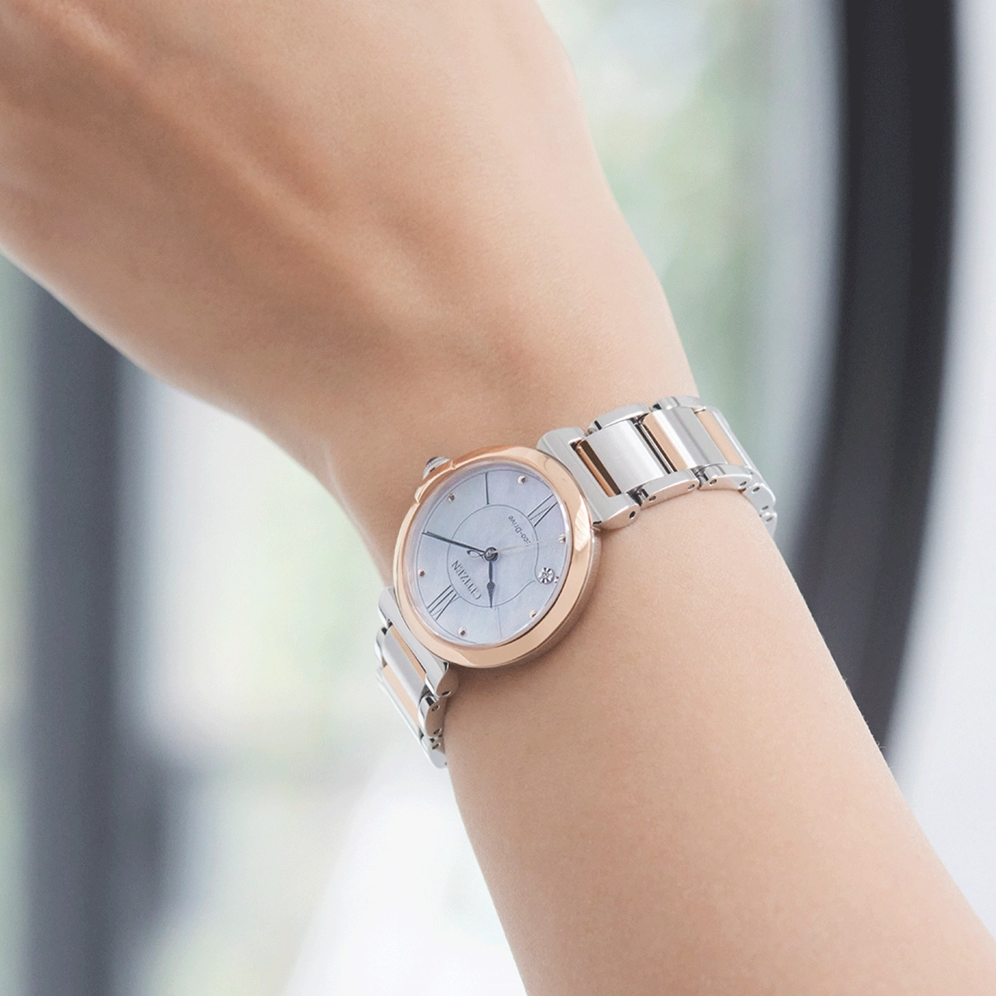 Pols horloge met een zilveren en roségouden band om een pols