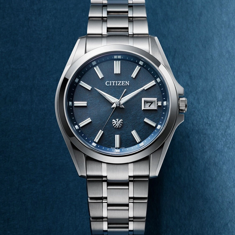 Citizen horloge met blauwe wijzerplaat en zilveren band op blauwe achtergrond.
