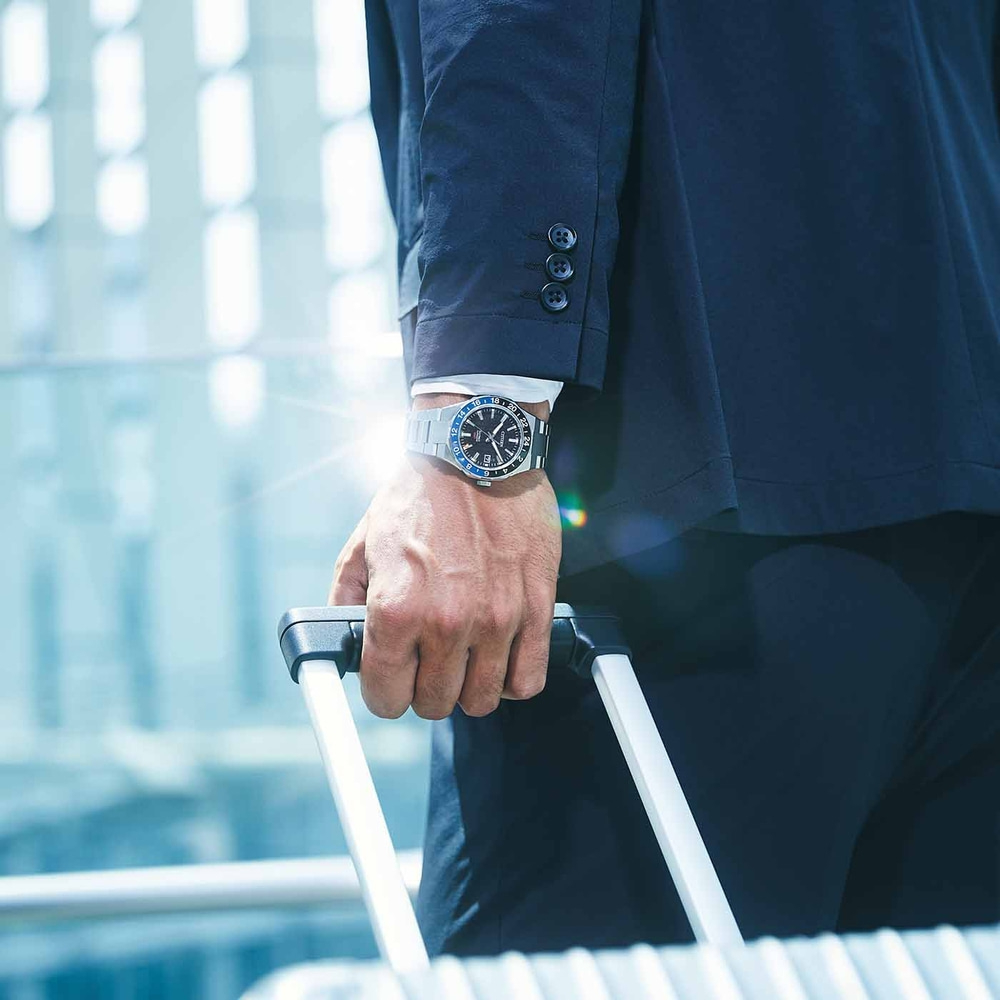 Man in pak met horloge die bagage vasthoudt, concept van zakenreizen.