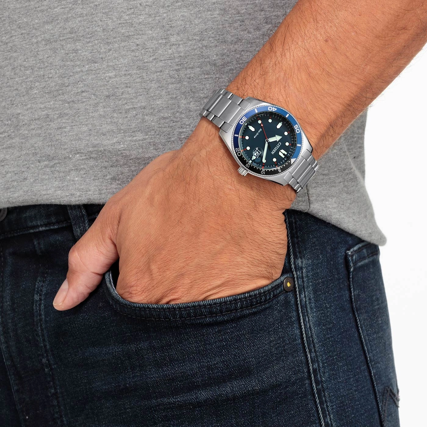 Man met Citizen horloge, hand in zak, blauwe jeans en grijs shirt.