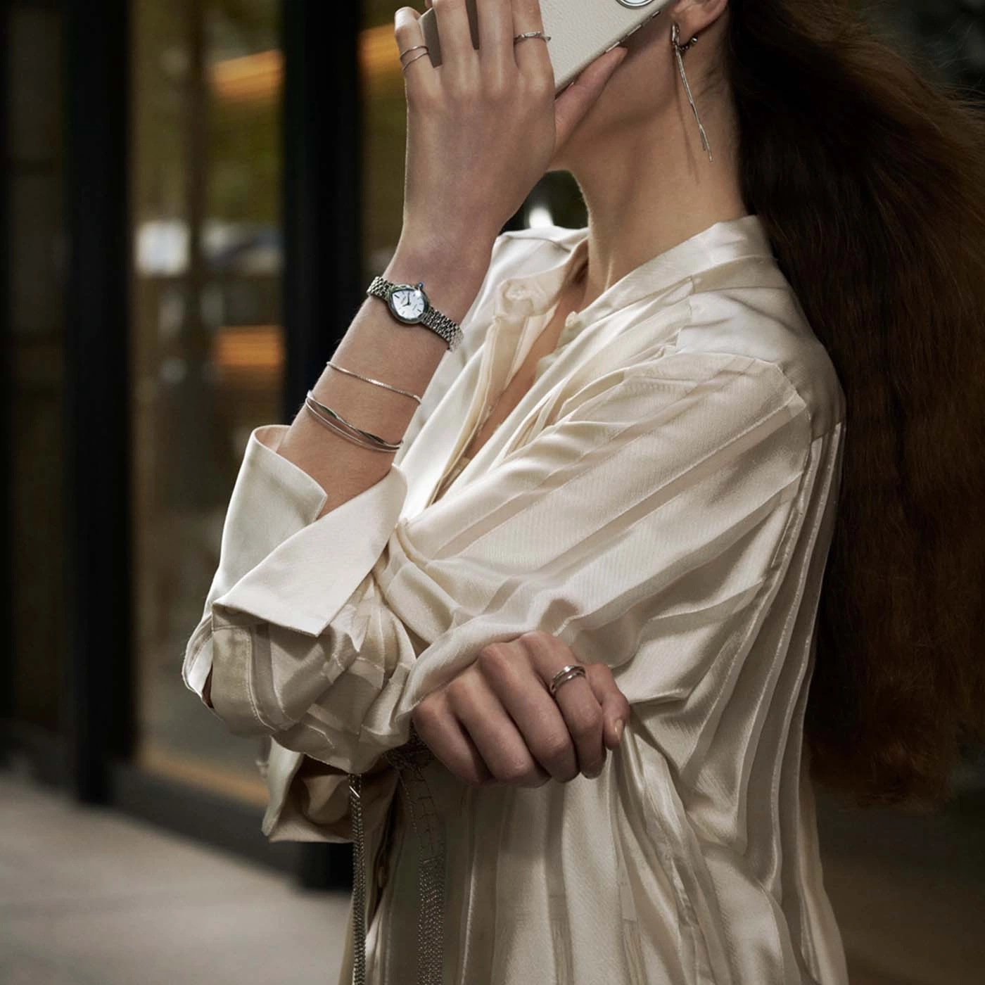 Vrouw draagt horloge en armbanden, houdt telefoon vast