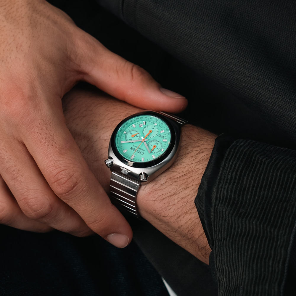 Een mannenpols toont een mintgroen Citizen chronograaf horloge met een roestvrijstalen band.