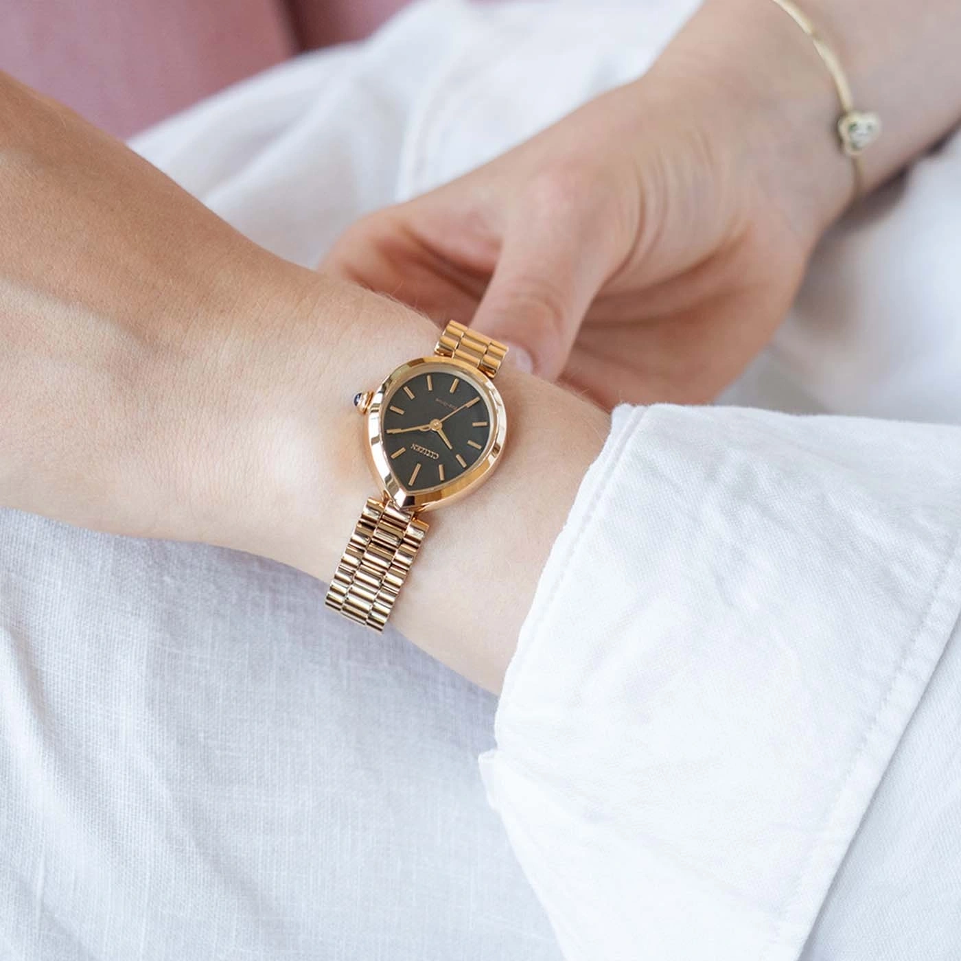 De pols van een vrouw draagt een gouden Citizen-horloge en armband.