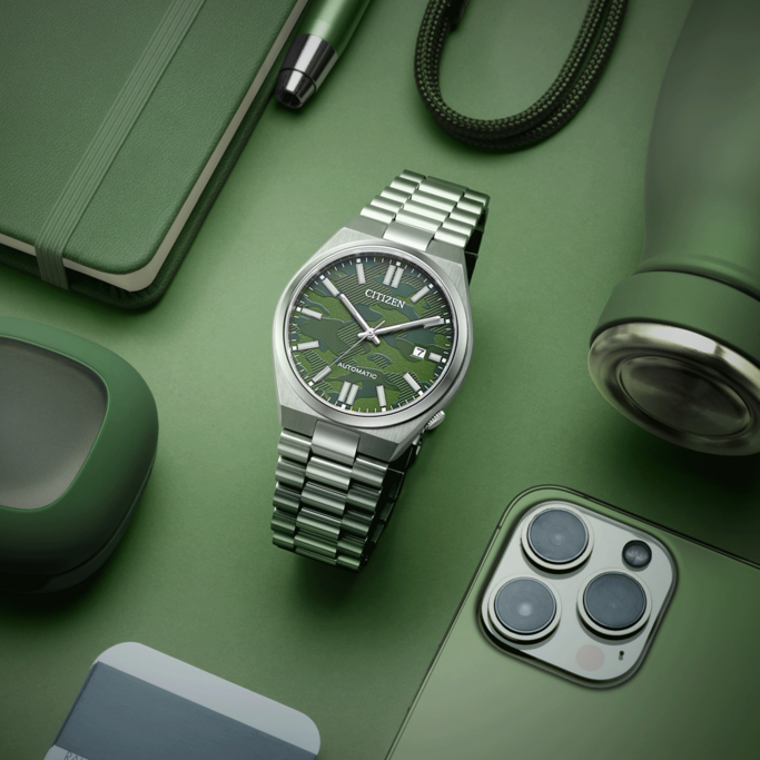 Groen horloge, telefoon, notitieboek, pen en waterfles op groene achtergrond.