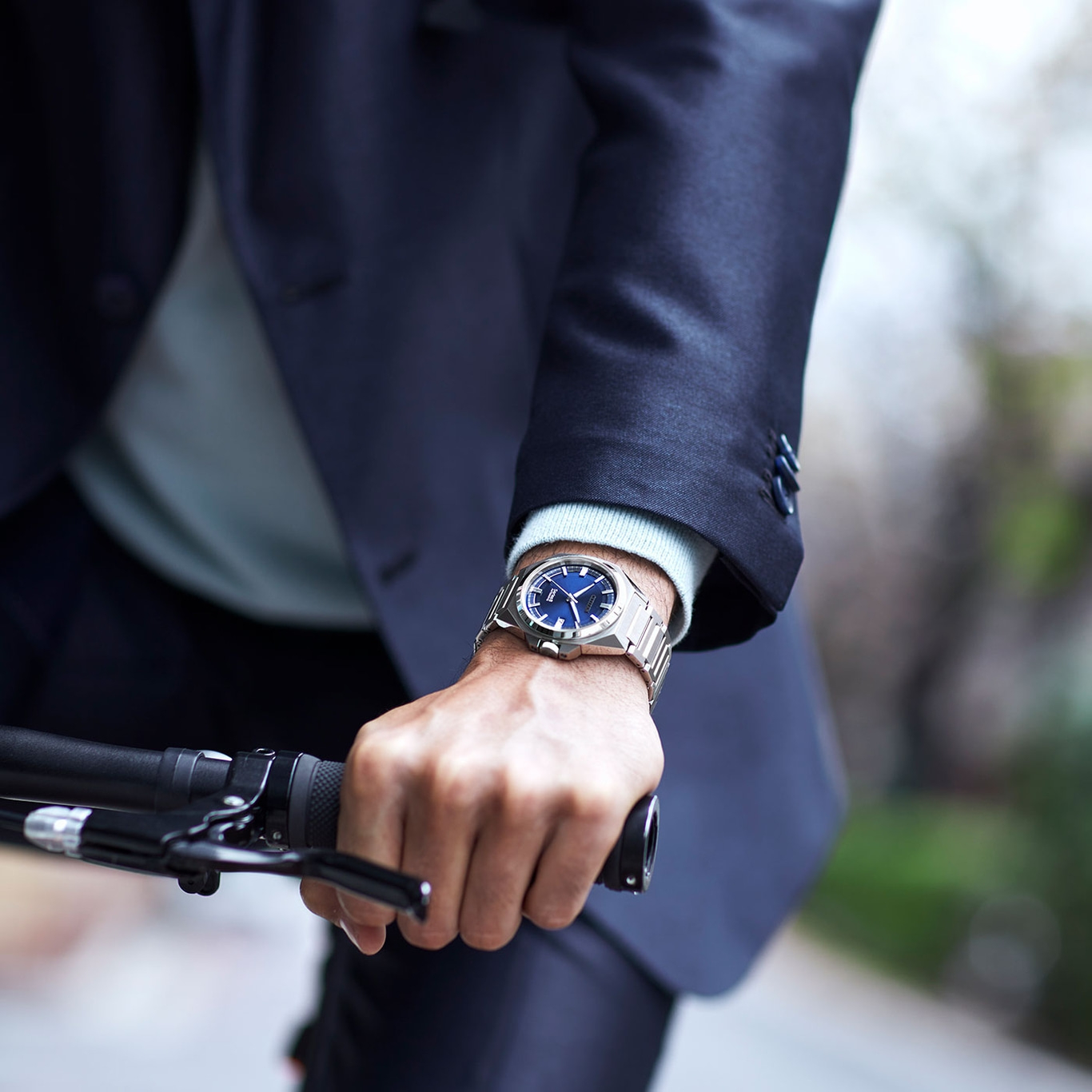 Man met horloge, houdt fietsstuur vast, draagt pak. Close-up.