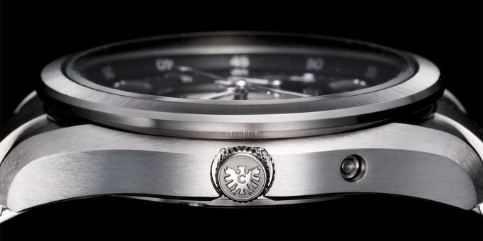 Close-up van een zilveren horloge met een zwarte wijzerplaat en ingewikkelde details.