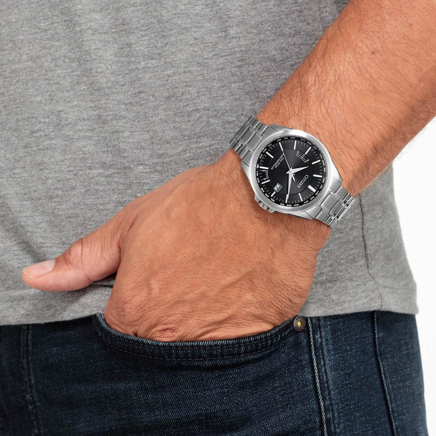 Man met Citizen horloge, hand in zak, grijs shirt, blauwe jeans.