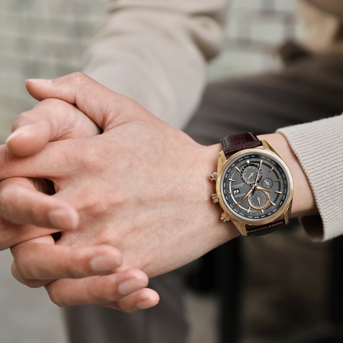 Man draagt een gouden Citizen horloge met een bruine leren band