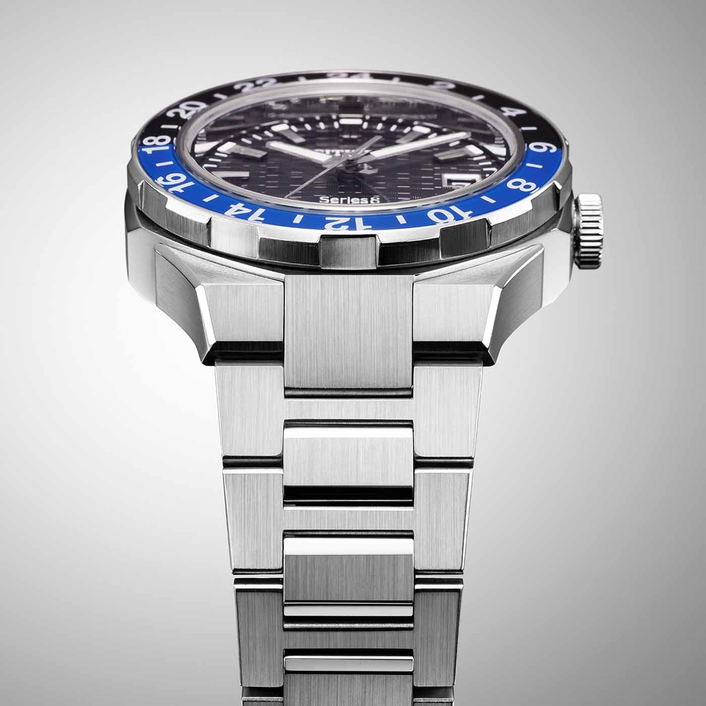 Close-up van een zilveren horloge met een blauw-zwarte bezel en een metalen band.
