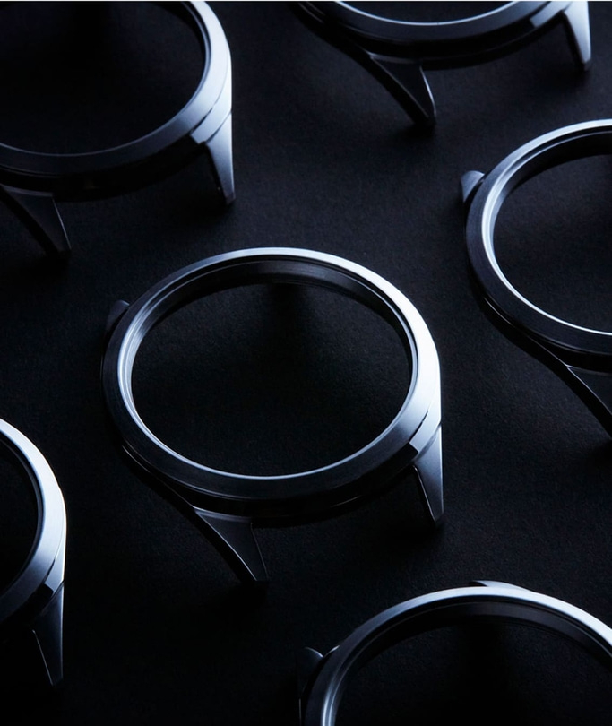 Horlogekasten gerangschikt op een donker oppervlak, metaalachtig en glanzend.