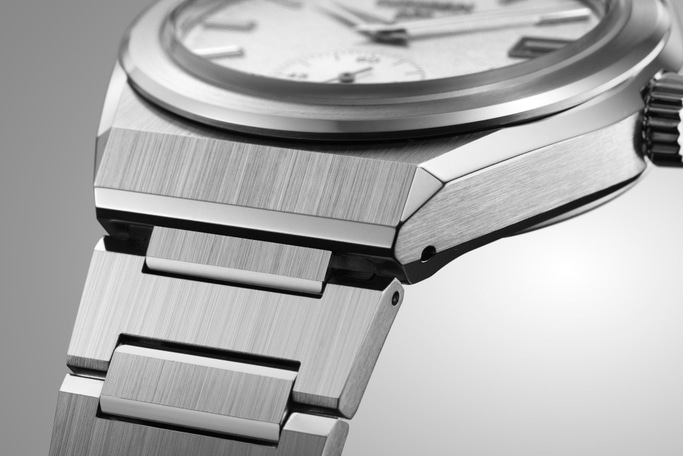 Close-up van een zilveren horloge met een geborstelde metalen afwerking en een gedetailleerd ontwerp.